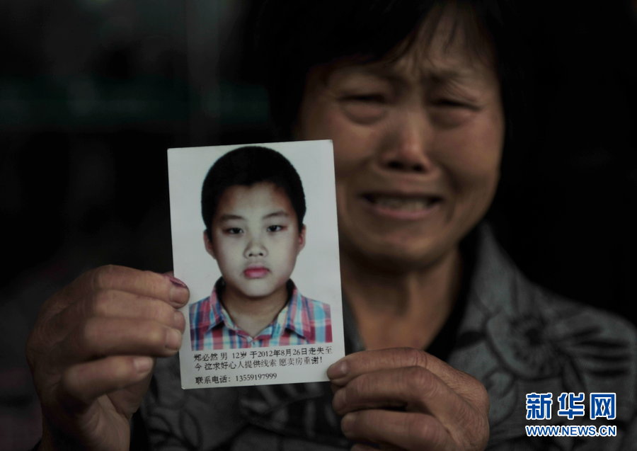 Yu Fanglan, aged over 70, kneels in front of the ticket office of North Coach Station of Fuzhou holding a picture of her lost grandson on Nov. 22, 2012. She was there to ask for help to find her 12-year-old grandson who disappeared three months ago.  Her grandson Zheng Biran went missing after visiting a friend on Aug.26, 2012. (Xinhua)