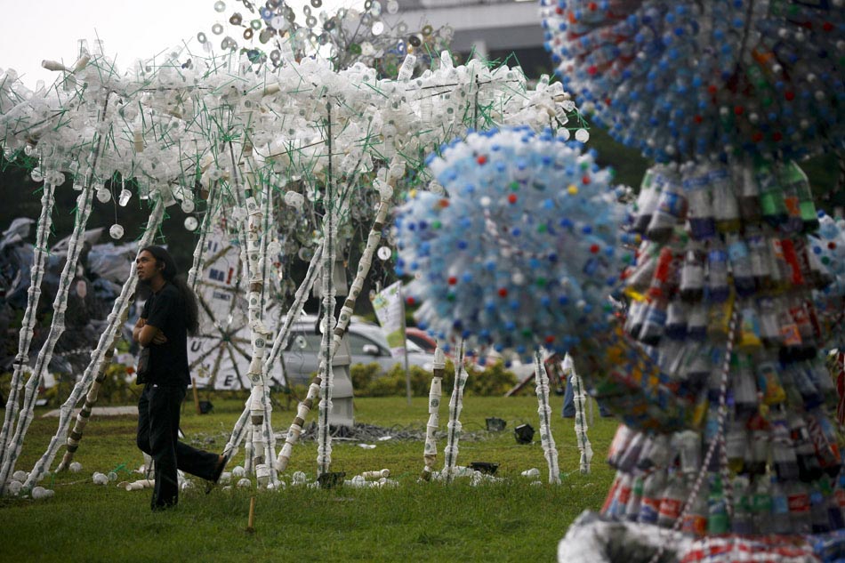 A youth enjoys watching the handicrafts made of abandoned coffee cups. The recycle of waste production reminds people to protect global environment and curb global warming. 