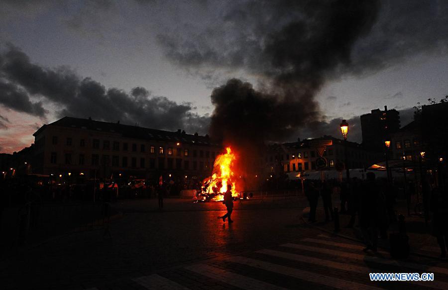 A man walks past the fire set up by dairy farmers during a protest against EU agricultural policies at the Place du Luxembourg, outside the European Parliament, in Brussels, capital of Belgium, on Nov. 26, 2012. Dairy farmers from all over Europe demonstrated today with about 1,000 tractors at the European Parliament in Brussels to protest against falling milk prices caused by overproduction in the continent. (Xinhua/Zhou Lei) 