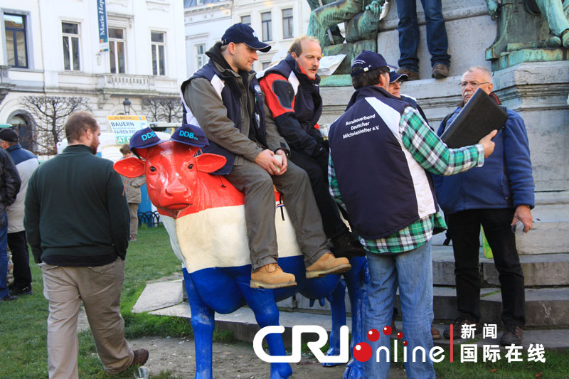 Demonstrators from the Netherlands sit on the statue of cow during a protest against E.U. agricultural policies at the Place du Luxembourg in Brussels, Belgium, Nov. 26, 2012. Dairy farmers from all over Europe demonstrated in Brussels on Monday to protest against falling milk prices caused by overproduction in the continent. (Photo/CRI Online)