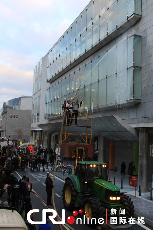 Dairy farmers spray milk to the European Parliament building on the lifting platform during a protest against E.U. agricultural policies at the Place du Luxembourg in Brussels, Belgium, Nov. 26, 2012. Dairy farmers from all over Europe demonstrated in Brussels on Monday to protest against falling milk prices caused by overproduction in the continent. (Photo/CRI Online)