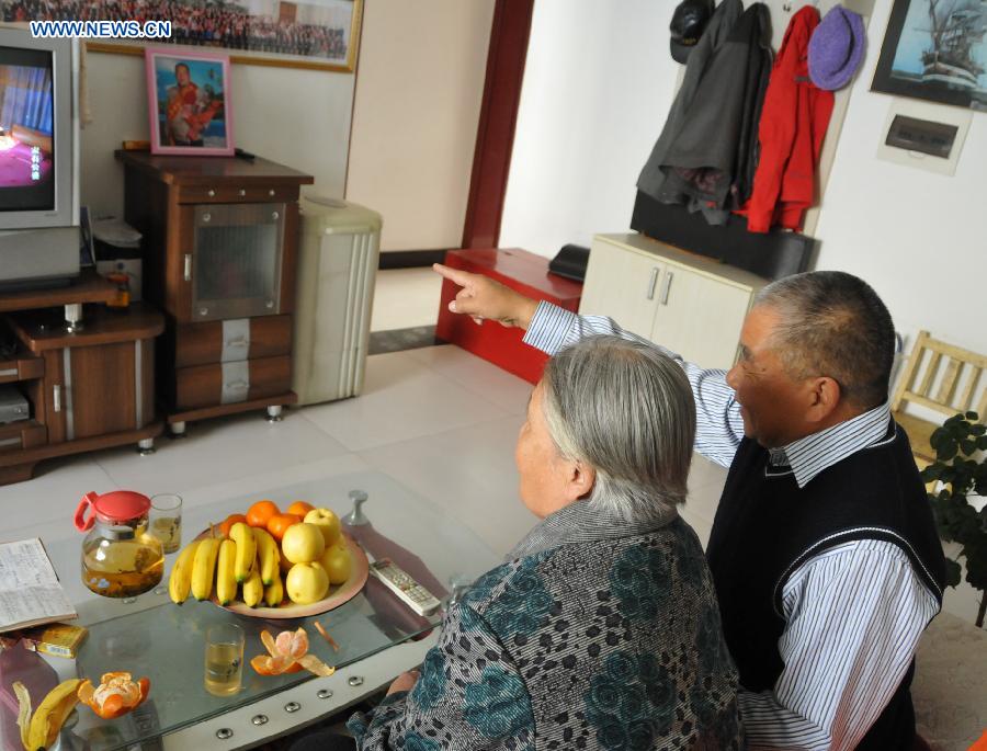 Zhu Qingzhang watches TV with his adoptive mother Han Fuzhen at home in Baotou, north China's Inner Mongolia Autonomous Region, Nov. 27, 2012. An accident left Zhu Qingzhang's adoptive mother Han Fuzhen in a vegetative state in 1975. Since then, Zhu has been looking after his adoptive mother while doing his own job. And all his love for his adoptive mother paid off when Han finally woke up 31 years later. Under the care of 62-year-old Zhu, 86-year-old Han now lives a happy and healthy life. (Xinhua/Liu Yide) 