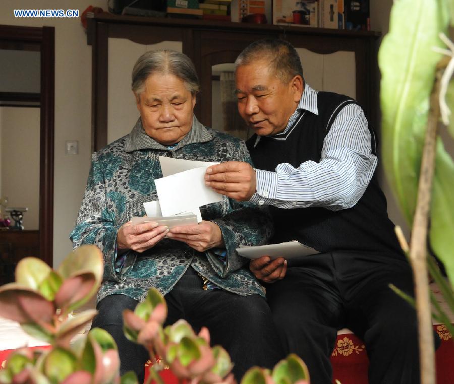 Zhu Qingzhang views old photos with his adoptive mother Han Fuzhen at home in Baotou, north China's Inner Mongolia Autonomous Region, Nov. 27, 2012. An accident left Zhu Qingzhang's adoptive mother Han Fuzhen in a vegetative state in 1975. Since then, Zhu has been looking after his adoptive mother while doing his own job. And all his love for his adoptive mother paid off when Han finally woke up 31 years later. Under the care of 62-year-old Zhu, 86-year-old Han now lives a happy and healthy life. (Xinhua/Liu Yide) 