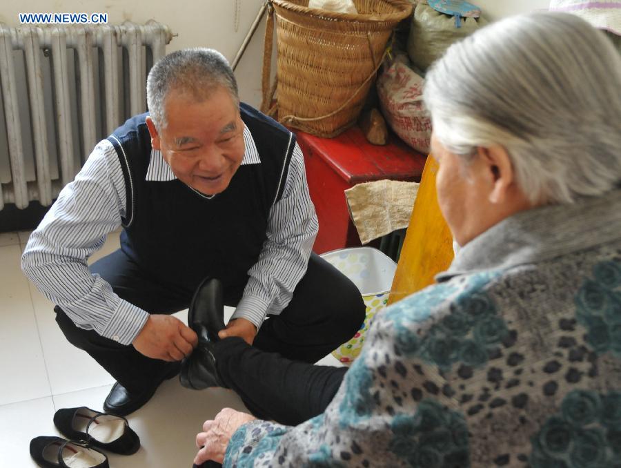 Zhu Qingzhang helps his adoptive mother Han Fuzhen put on her cotton shoes at home in Baotou, north China's Inner Mongolia Autonomous Region, Nov. 27, 2012. An accident left Zhu Qingzhang's adoptive mother Han Fuzhen in a vegetative state in 1975. Since then, Zhu has been looking after his adoptive mother while doing his own job. And all his love for his adoptive mother paid off when Han finally woke up 31 years later. Under the care of 62-year-old Zhu, 86-year-old Han now lives a happy and healthy life. (Xinhua/Liu Yide) 