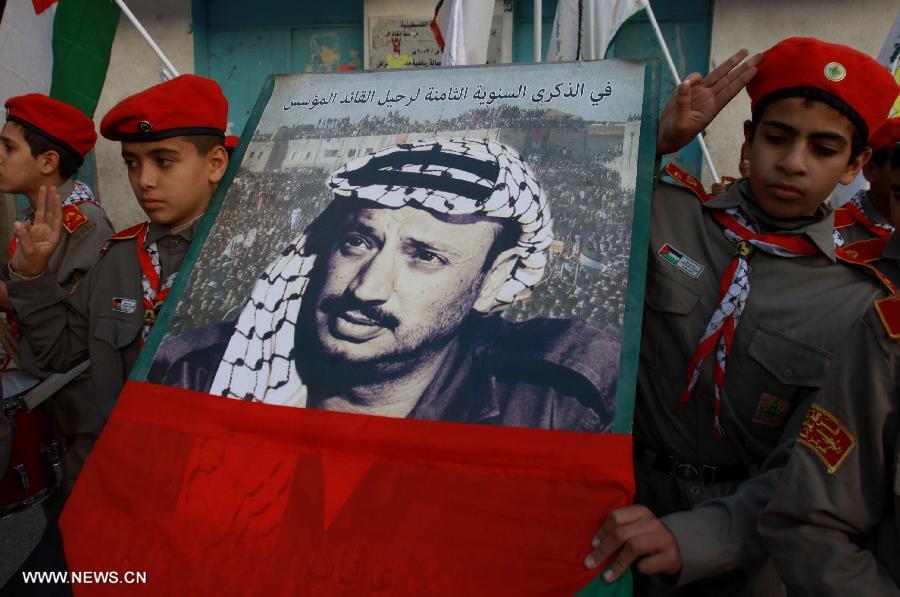 Palestinian students hold a poster of the late Palestinian leader Yasser Arafat during a memorial ceremony at a school in the West Bank city of Nablus, on Nov. 27, 2012. Palestinian engineers dug up the tomb of Arafat to take samples from his remains for poison tests at dawn Tuesday, sources said. (Xinhua/Nidal Eshtayeh)