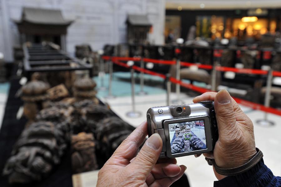 A local resident takes pictures of items displayed at an exhibition of ancient Chinese architectural woodcarving components in Jinan, capital of east China's Shandong Province, Nov. 29, 2012. (Xinhua/Guo Xulei)