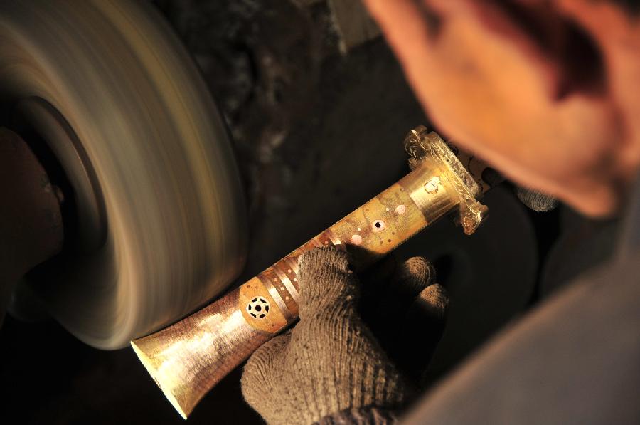 A craftsman of China's Bao'an ethnic group polishes the handle of a broadsword in Jishishan County, northwest China's Gansu Province, Nov. 29, 2012. (Xinhua/Huang Wenxin) 