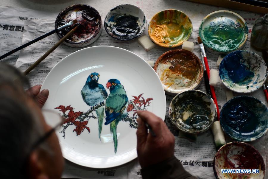 Bian Xiping, inheritor of intangible cultural heritage ceramic arts and crafts, paints on a ceramic plate by using traditional skills in Huating County, northwest China's Gansu Province, Nov. 29, 2012. 