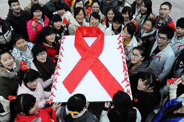 Volunteers from the Youth Volunteers Association at Fuyang Teachers College show a red ribbon publicity board in Fuyang, East China's Anhui province on Nov 29, 2012. The college launched a publicity and education campaign, making AIDS publicity boards, to raise students' awareness of AIDS prevention and appeal to society to take care of AIDS patients. (Xinhua)
