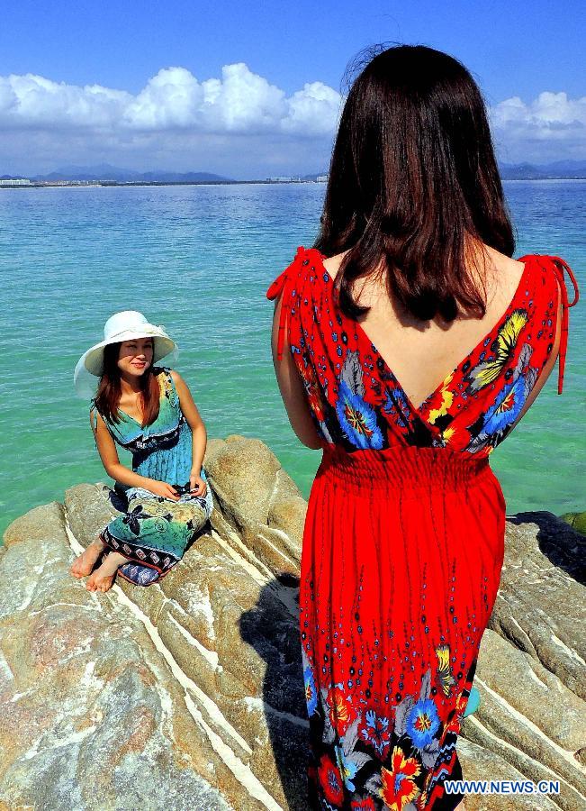 Two women take pictures by the seaside of Sanya, a famous tourism city in south China's Hainan Province, Dec. 1, 2012. As Sanya has entered its tourist season, more tourists are seen here. (Xinhua/Wang Song)