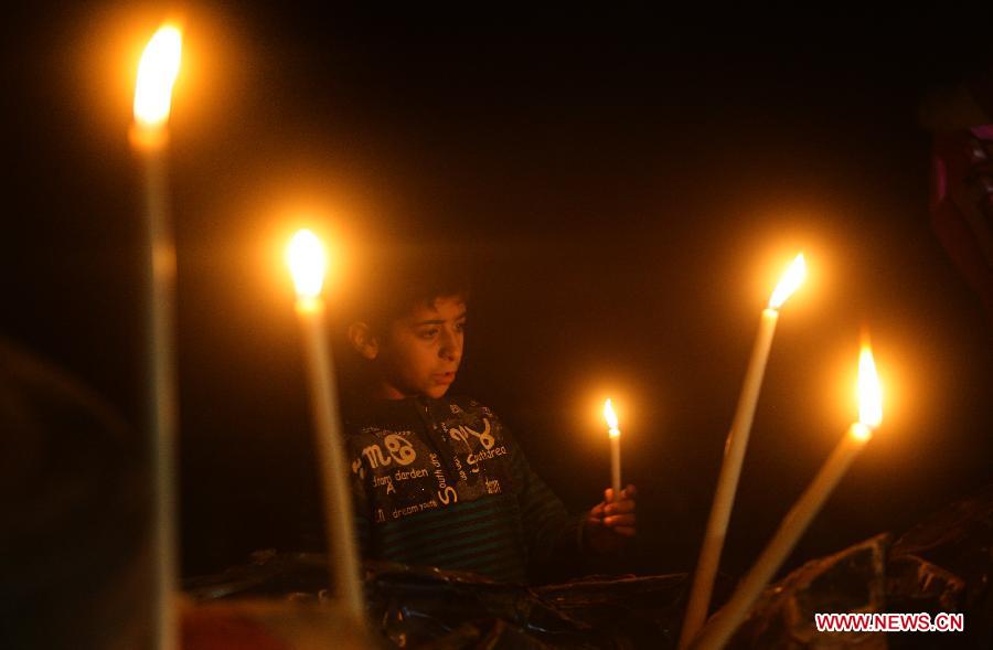 A Palestinian kid lights a candle around the destroying house of Al-Dalou family in Gaza City on Dec. 1, 2012. An Israeli bomb fell upon Al-Dalou family's two-storey house in Gaza City's residential al-Nasser neighborhood on Nov.18, killing 11, including four children and a woman as old as 81. It was one of the deadliest events in the latest conflict between Israel and Gaza militants. (Xinhua/Yasser Qudih)