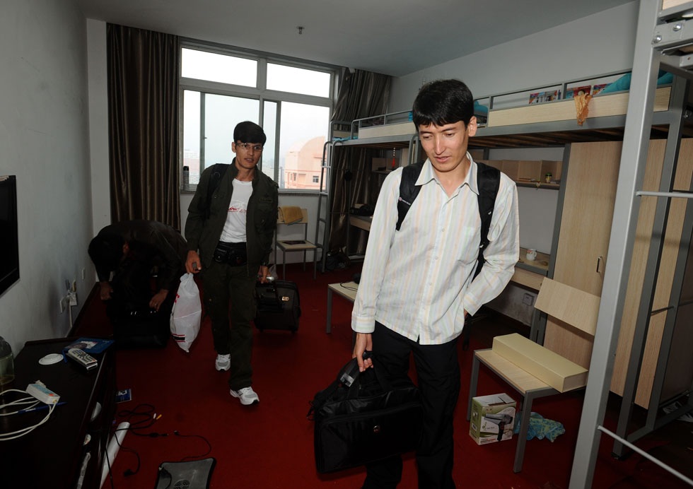 Salman Raha (R) carrying baggage walks out of his dormitory at Taiyuan University of Technology in Taiyuan, capital of north China's Shanxi Province, July 11, 2012.  