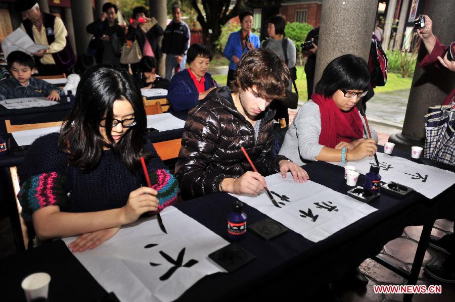 A French exchange student (C, front) experiences writing Chinese calligraphy during an activity at Taipei Confucius Temple in Taipei, southeast China's Taiwan Province, Dec. 2,2012. (Xinhua/Wu Ching-teng)