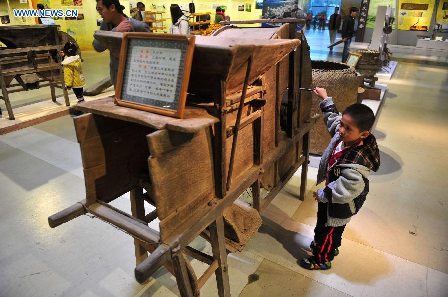 A young boy tries to operate a farm tool during an exhibition on farming culture of Zhuang ethnic group in Nanning, capital of southwest China's Guangxi Zhuang Autonomous Region, Dec. 1, 2012. (Xinhua/Huang Xiaobang)