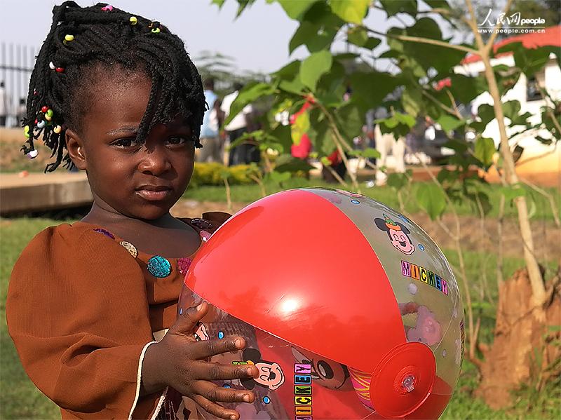 A little girl holds a “Mickey Mouse” inflatable balloon.(People's Daily Online/ Li Liang)