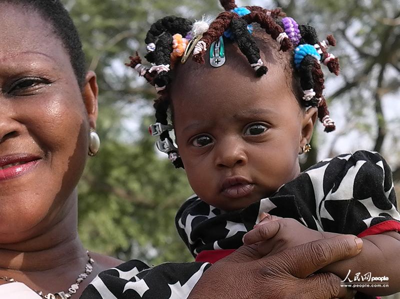 A baby girl with braids is held by her mother. (People's Daily Online/ Li Liang)