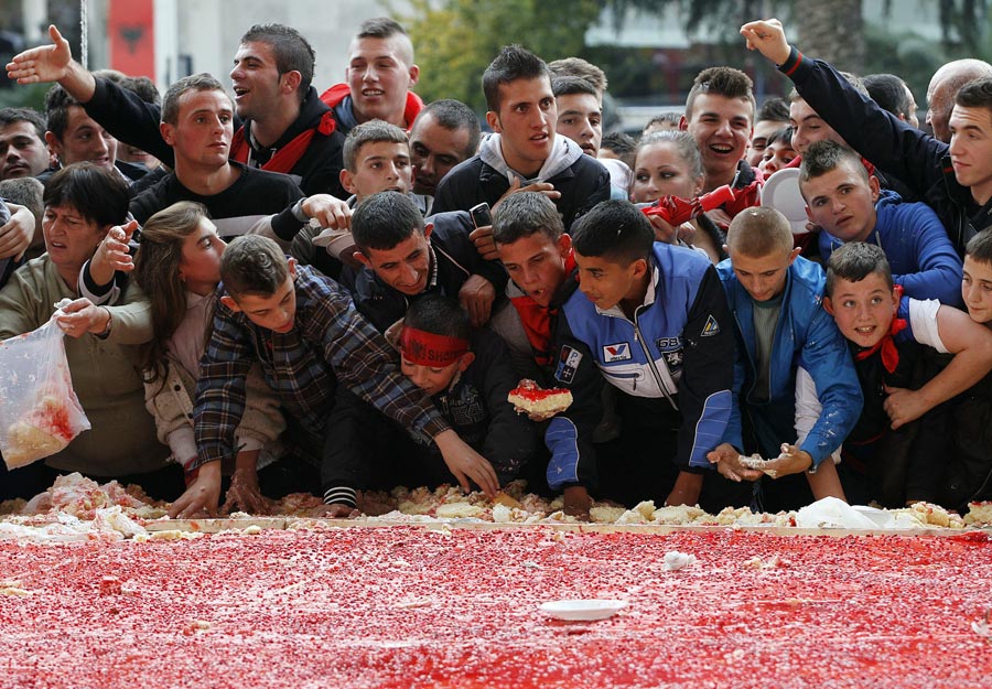 Children eat pieces of a giant cake, with the Albanian flag symbols and measuring 550 square metres (5920 square feet), prepared for the celebration of Albania's 100th Year of Independence in Tirana November 28, 2012.  (Xinhua/Reuters Photo)