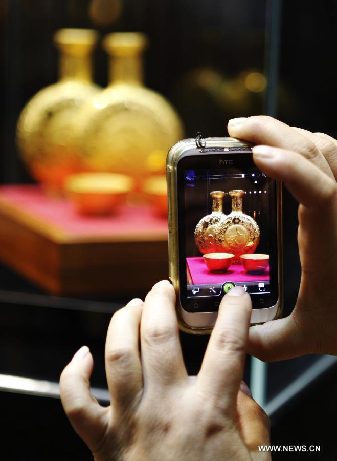 A visitor takes photos of a work of art which is made of gold at the 8th Beijing International Finance Conference in Beijing, capital of China, Dec. 3, 2012. The four-day conference was closed on Monday. (Xinhua/Wang Shen)