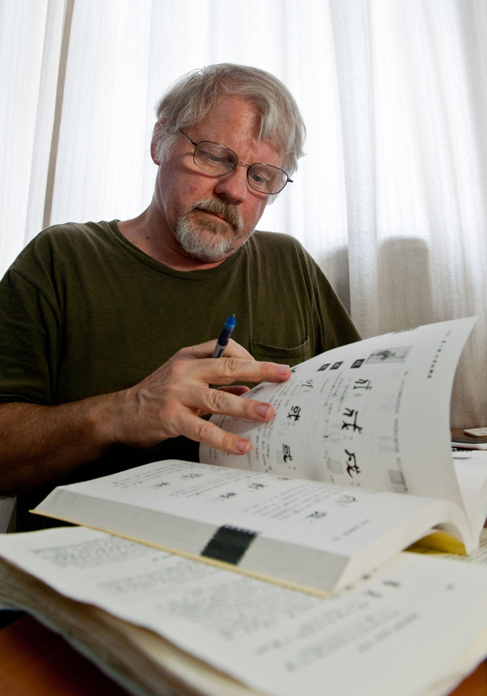 Richard Sears studies the origins of Chinese characters in his single-room apartment in Tianjin, north China, Aug. 8, 2012.(Xinhua Photo)