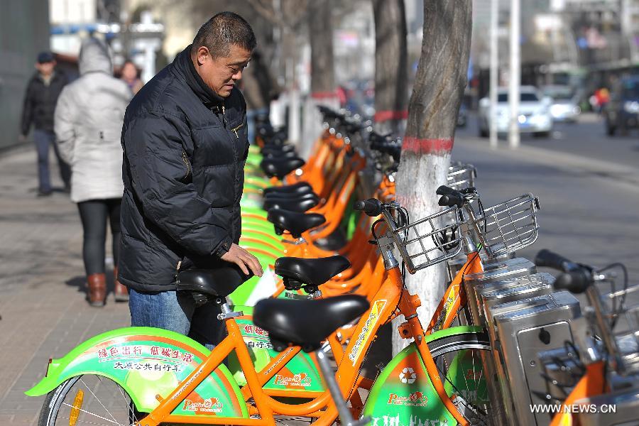 A man picks up a public bike in a renting spot in Taiyuan, capital of north China's Shanxi Province, Dec. 5, 2012. Upon the end of November this year, there were 491 renting spots for public bikes in Taiyuan. A total of over 11,000 public bikes had been put into use. (Xinhua/Zhan Yan)