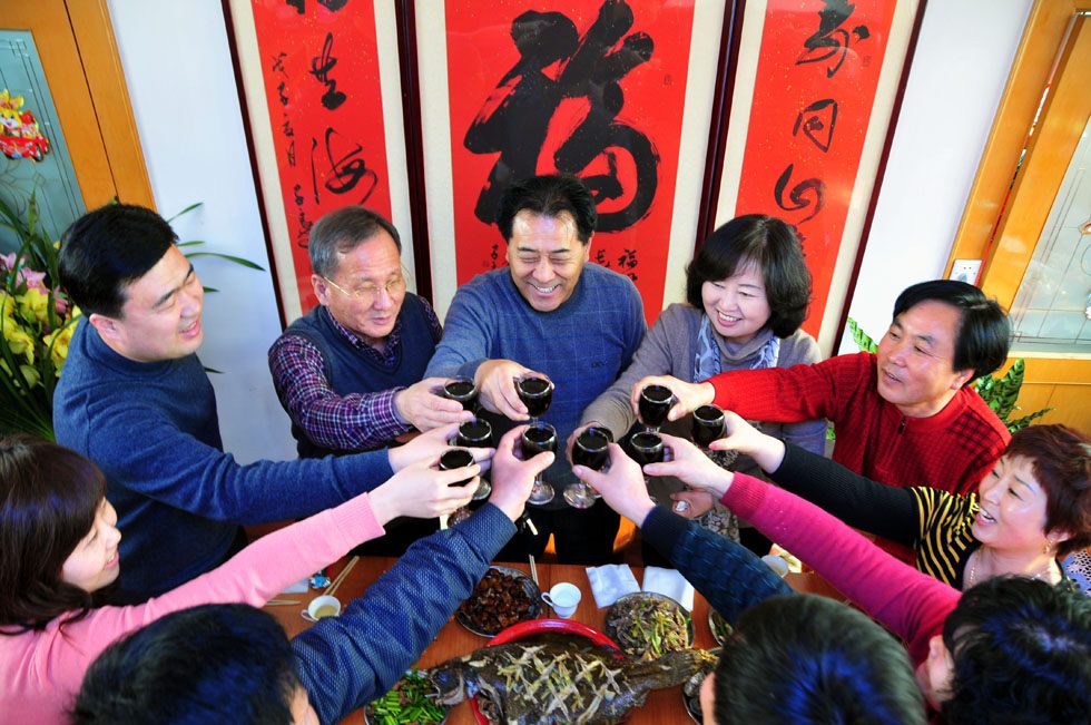 Kim Byungcho (3rd L) and his wife (5th L) enjoy a feast with neighbours in Dongli Village of Rushan, east China's Shandong Province, Jan. 22, 2012. (Xinhua Photo) 