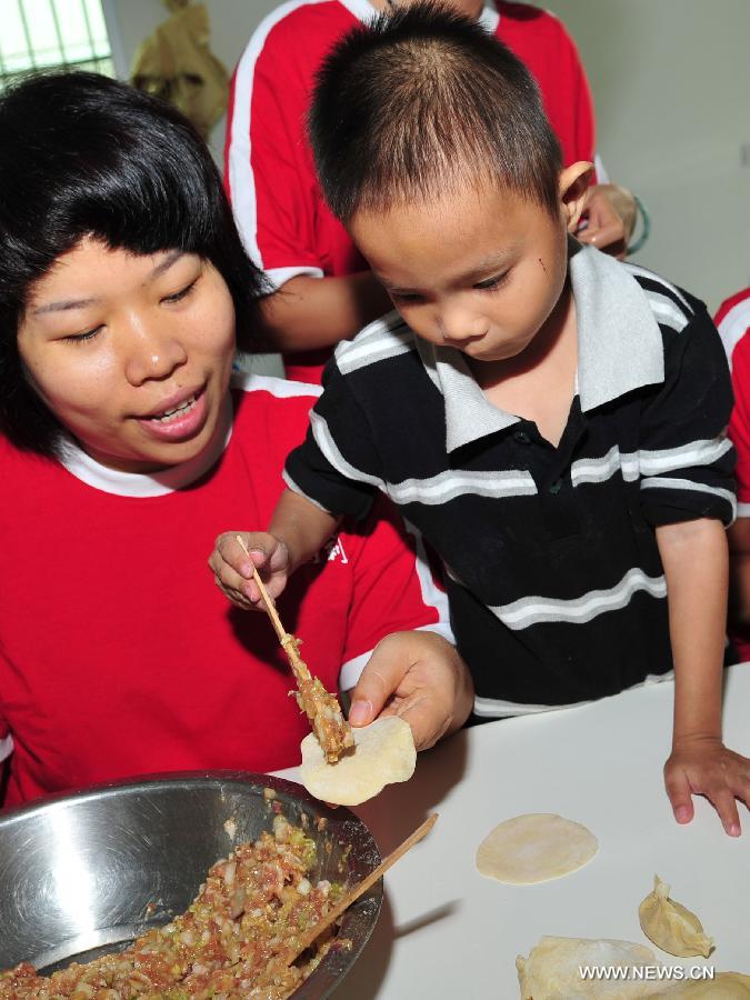 A volunteer wraps up dumplings with a child at a welfare house in Sanya, south China's Hainan Province, Dec. 5, 2012. Many Chinese volunteers make their contributions to the society on Wednesday, to mark the International Volunteer Day, which is an international observance designated by the United Nations since 1985. (Xinhua/Hou Jiansen) 
