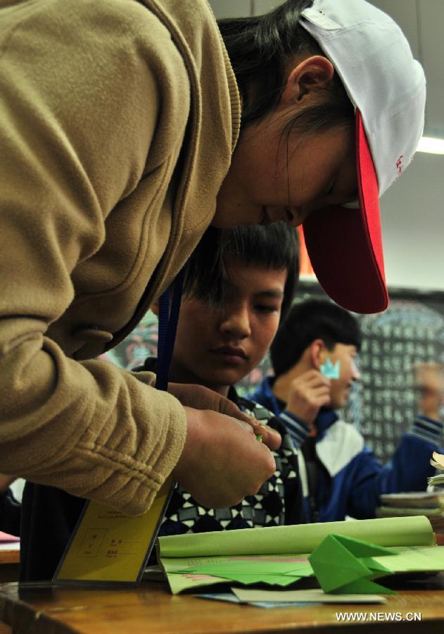 A volunteer (front) from Lanzhou University of Technology help a deaf student make origami at Lanzhou School for the Blind, Deaf and Dumb in Lanzhou, capital of northwest China's Gansu Province, Dec. 4, 2012, a day ahead of the International Volunteer Day. The International Volunteer Day, which falls on Dec. 5 every year, is an international observance designated by the United Nations since 1985. (Xinhua/Huang Wenxin) 