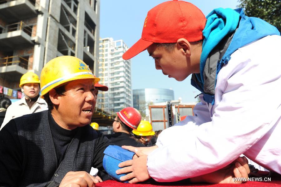 A volunteer from Anhui Chinese Traditional Medicine Institute checks blood pressure for a migrant worker in Hefei, capital of east China's Anhui Province, Dec. 5, 2012. Many Chinese volunteers make their contributions to the society on Wednesday, to mark the International Volunteer Day, which is an international observance designated by the United Nations since 1985. (Xinhua/Liu Junxi) 