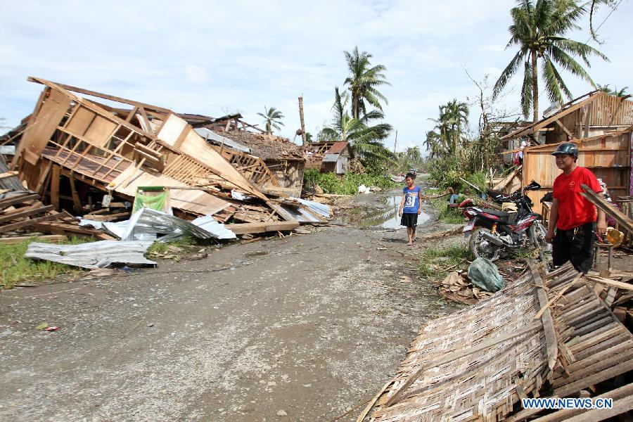 People stand beside damaged houses after typhoon Bopha hit New Bataan town in southern province of Compostela Valley, the Philippines, Dec. 5, 2012. The death toll from typhoon Bopha, locally known as Pablo, rises to 224, as Bopha continues to ravage several southern Philippine provinces. (Xinhua/JEMA)