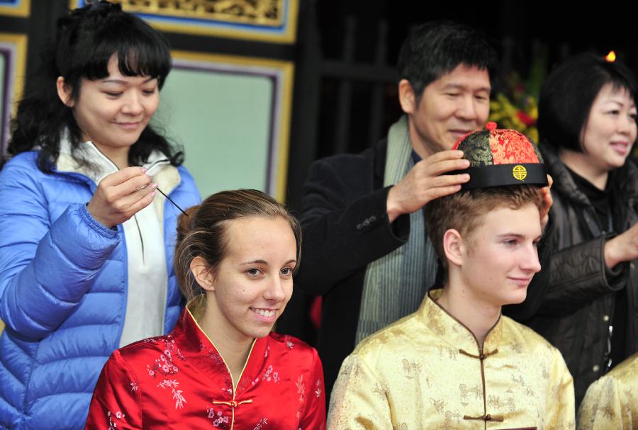 Two exchange students get their capping ceremony and hair-pinning ceremony at Taipei Confucius Temple during their coming-of-age ceremony in Taipei, southeast China's Taiwan, Dec. 9,2012. In total 130 exchange students from 18 countries and regions attend their coming-of-age ceremony on Sunday, including capping ceremony for boys and hair-pinning ceremony for girls. (Xinhua/Wu Ching-teng)