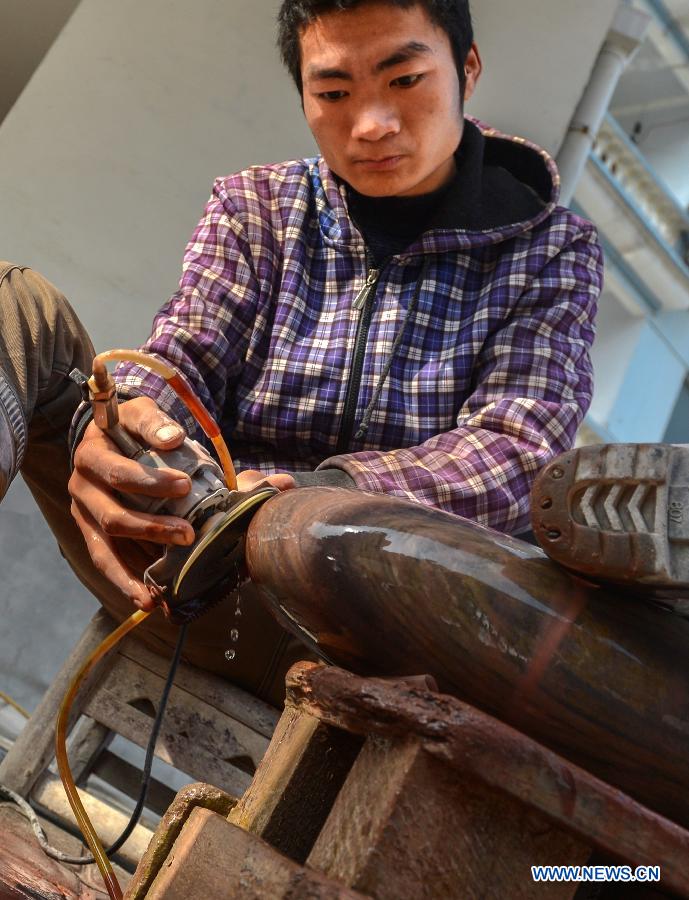 A craftsman does polishing work on a cut stone in Changyang Tujia Autonomous County, central China's Hubei Province, Dec. 8, 2012. Located close to the Qingjiang River, the county is abundant in "Qingjiang Stone", of which natural colors and grains enable people here to develop it into ornamental stones. The stone industry has provided over 35,000 jobs for the people in the county, contributing greatly to the local economic development. (Xinhua/Cheng Min)