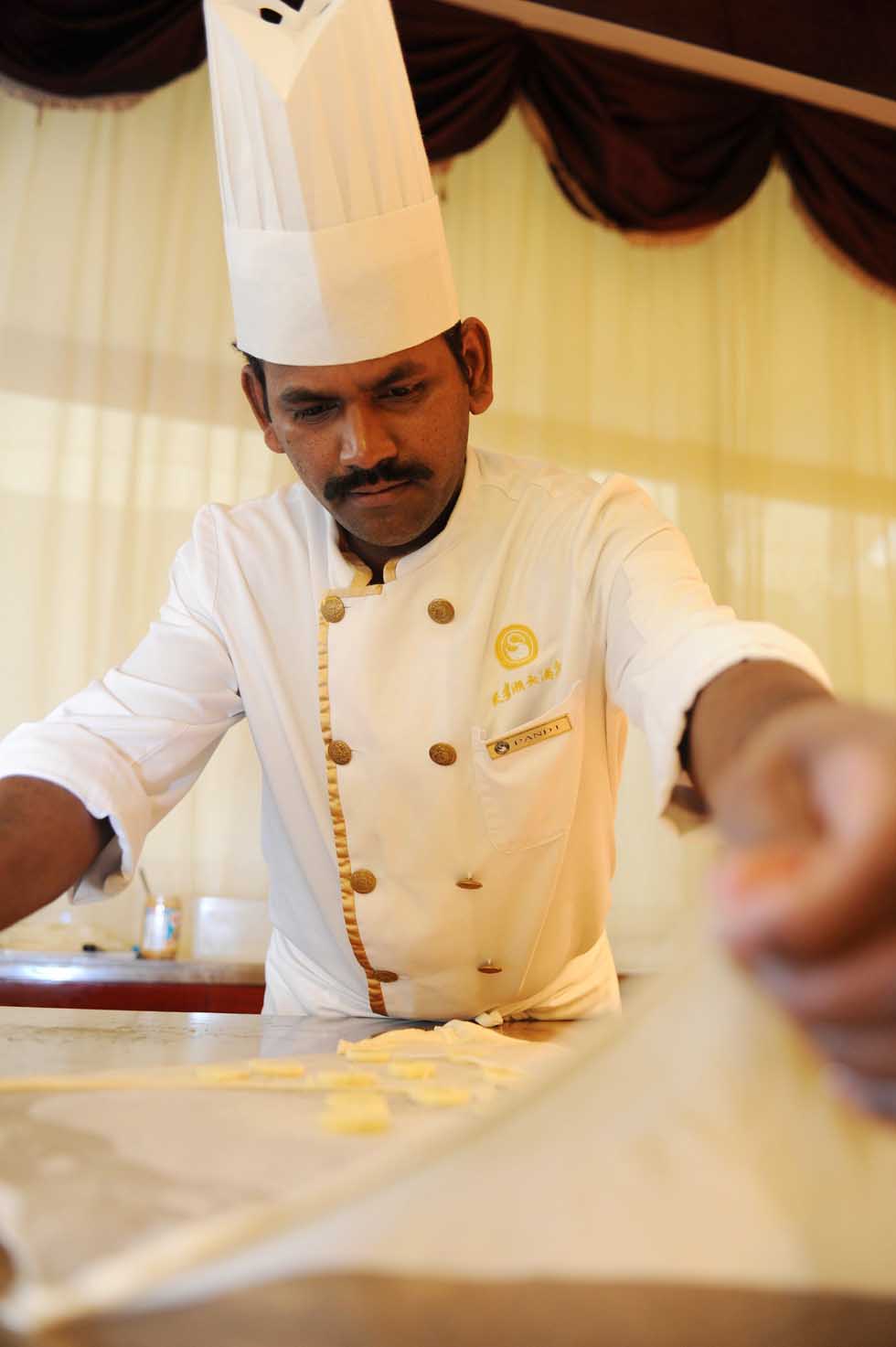 Pandi places chipped banana onto a piece of pancake for a roti prata in a buffet restaurant in Hefei, capital of east China's Anhui Province, June 14, 2012.