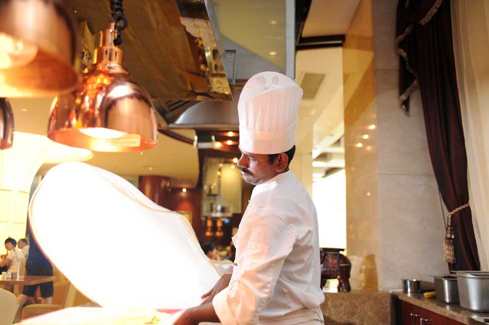 Pandi waves a piece of pancake for a roti prata in a buffet restaurant in Hefei, capital of east China's Anhui Province, June 14, 2012.