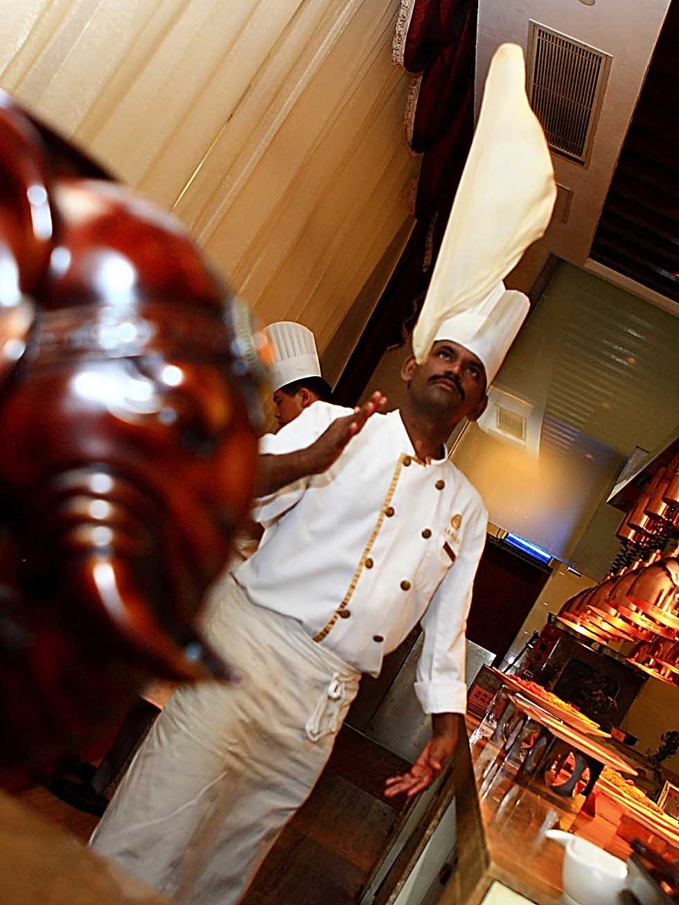 Pandi waves a piece of pancake for a roti prata in a buffet restaurant in Hefei, capital of east China's Anhui Province, June 14, 2012.