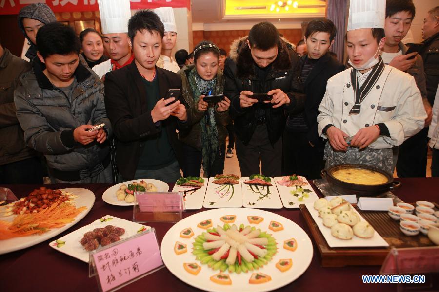 Visitors take photos of dishes during a culinary contest in Neijiang, southwest China's Sichuan Province, Dec. 10, 2012. A total of 16 cooks attended the contest held here on Monday. (Xinhua/Lan Zitao) 