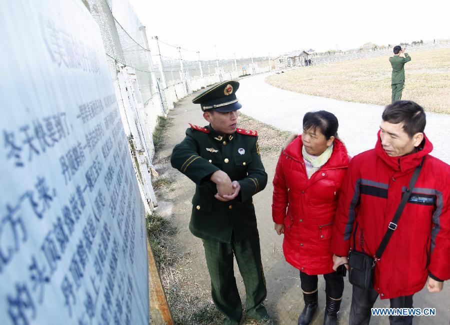 A soldier (L) from Yancheng border detachment reminds tourists of protecting rare birds at national nature reserve of rare birds in Yancheng, east China's Jiangsu Province, Dec. 11, 2012. The reserve was set to protect rare birds such as red-crowned cranes since 1980s. Over the past 30 years, soldiers here have been protecting the rare birds and wetlands. (Xinhua/Zhang Shanyu)