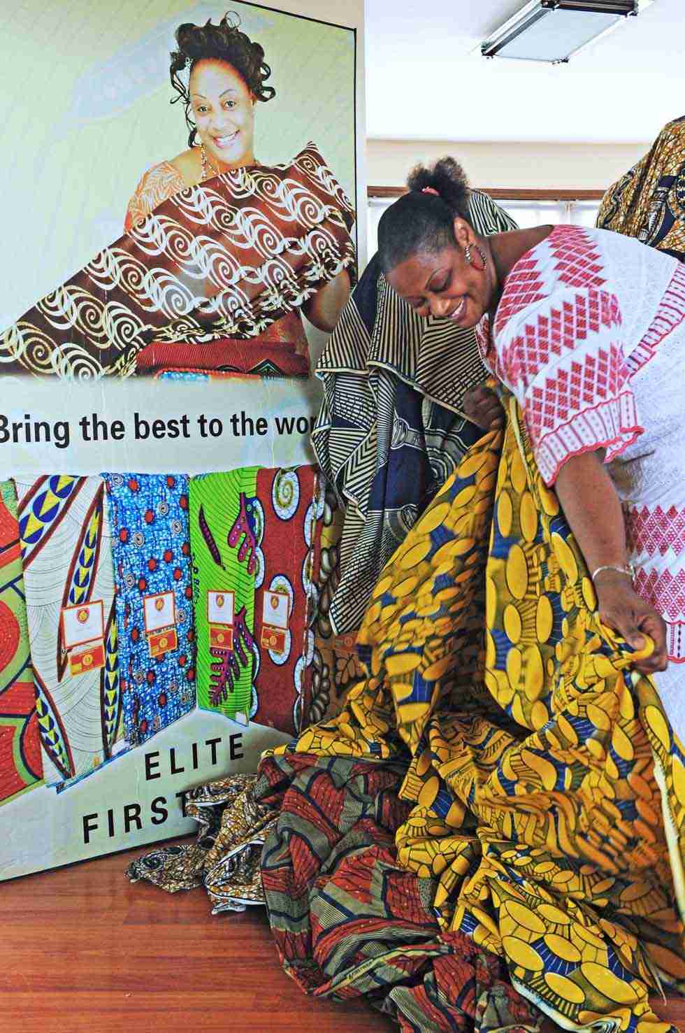 Senegalese merchant Mamadou Sall's wife Fatima arranges cloth in front of a large advertisement board featuring herself in Sall-Industrial Co., Ltd. in Yiwu, east China's Zhejiang Province, July 15, 2012. (Xinhua/Tan Jin) 