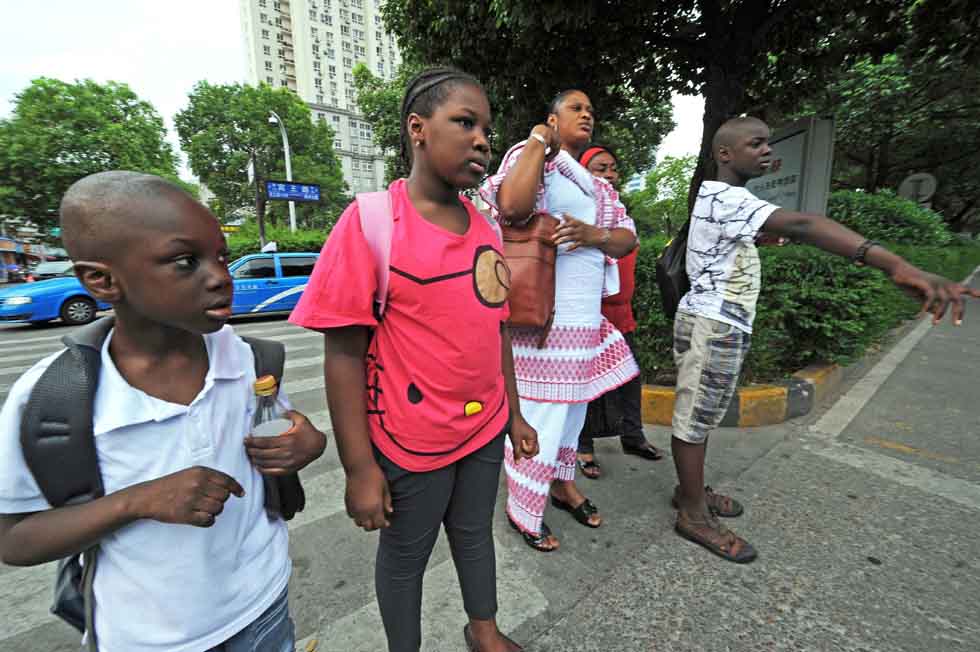 Senegalese merchant Mamadou Sall's wife Fatima (3rd L), their first son Muhammed (1st R), daughter Kineh (2nd L) and second son Abdoulaye (1st L) hail a taxi to return home in Yiwu, east China's Zhejiang Province, July 15, 2012. (Xinhua/Tan Jin) 