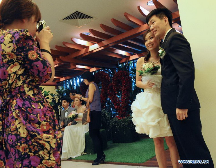 A couple pose for photos as they wait to solemnize their marriage at the Singapore Registry of Marriage, Dec. 12, 2012. A total of 541 couples applied to solemnize their marriage in Singapore on Dec. 12, 2012, hoping that the "triple 12 day" will bring them good luck. (Xinhua/Then Chih Wey) 