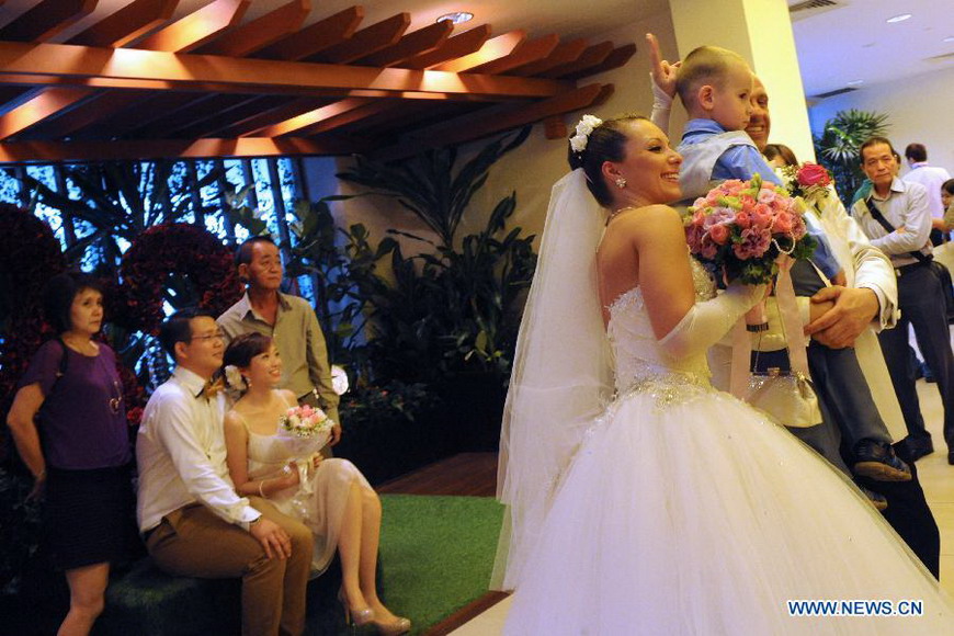 A couple pose for photos as they wait to solemnize their marriage at the Singapore Registry of Marriage, Dec. 12, 2012. A total of 541 couples applied to solemnize their marriage in Singapore on Dec. 12, 2012, hoping that the "triple 12 day" will bring them good luck. (Xinhua/Then Chih Wey) 