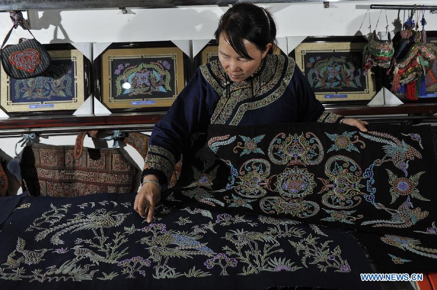 Wei Taohua, a horse-tail embroidery craftswoman of Shui ethnic group, checks finished horsetail embroidery works in Sandu, southwest China's Guizhou Province, Dec. 12, 2012. (Xinhua/Ou Dongqu)