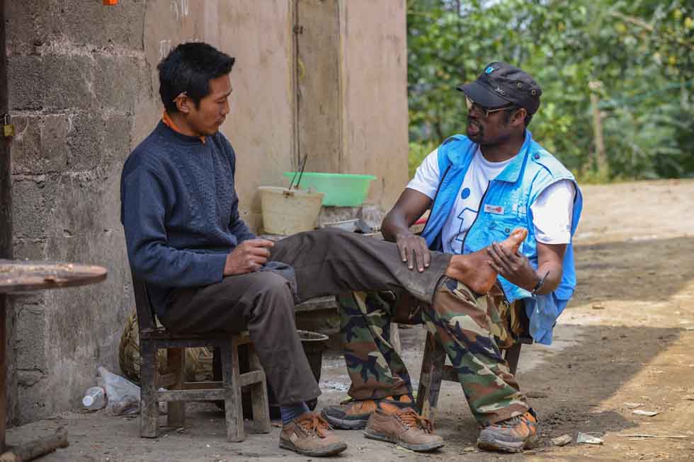 Diarra Boubacar (R) checks a foot of villager Chen Degang whose foot has strained in Boyi Village, Luozehe Town, Yiliang County, southwest China's Yunnan Province, Sept. 15, 2012.(Xinhua/Li Xin)