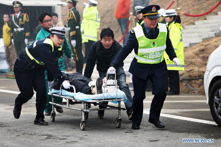 Staff members of road administration department rescue an "injured" person during the 2012 highway traffic emergency drill in Yingshan County, central China's Hubei Province, Dec. 13, 2012. The drill held on Thursday involved over 800 personnel from armed police, fire control, medical rescue and other departments. (Xinhua/Wan Xiang) 