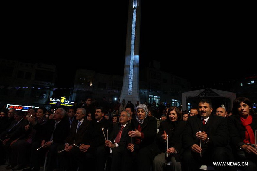 Palestinian Prime Minister Salam Fayyad (5th R, front) holds candles as he attends a celebration to inaugurate Christmas' decorations in the West Bank city of Ramallah, on Dec. 12, 2012. (Xinhua/Pool) 