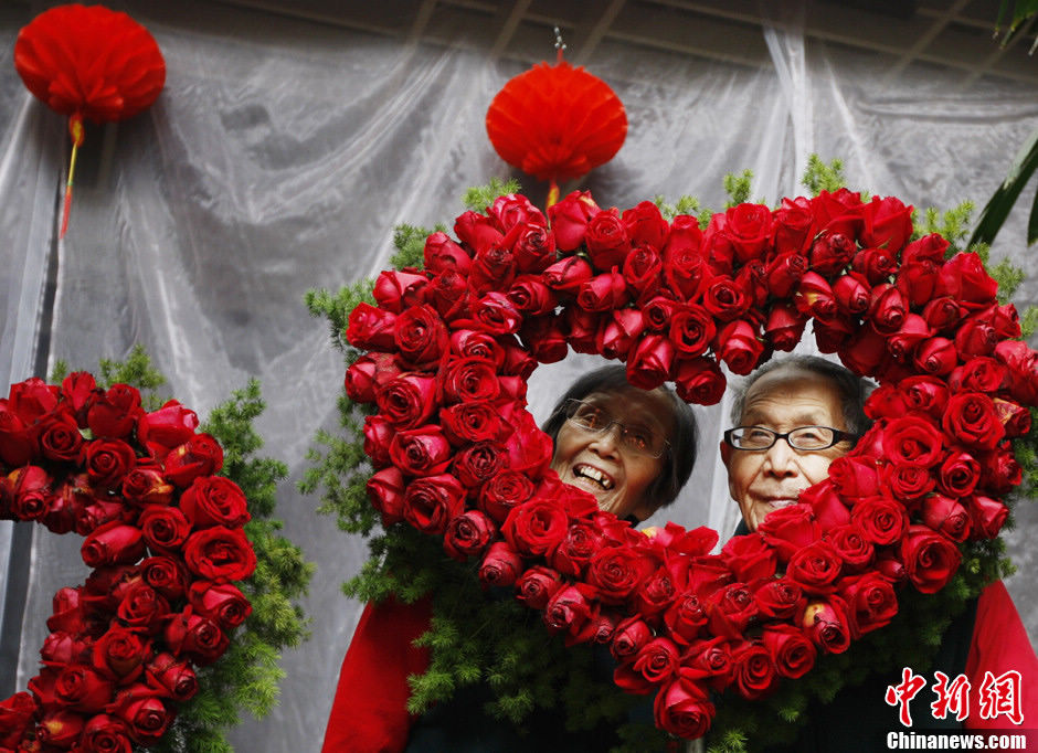 A couple takes celebrating their golden wedding photo in front of the "heart" type garland on Feb. 14, 2012. (Chinanews)
