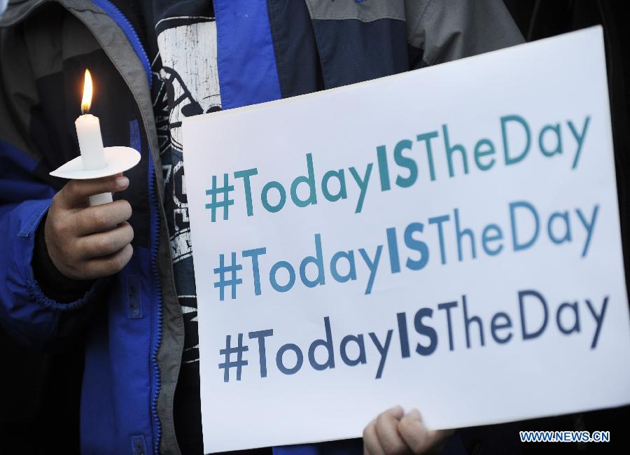 A supporter of gun control legislation holds a candle and a placard during a rally to pay respect for the shooting victims in front of the White House in Washington, capital of the United States, Dec. 14, 2012, following a deadly shooting spree in an elementary school in Newtown, Connecticut, which took place earlier in the day. (Xinhua/Zhang Jun) 