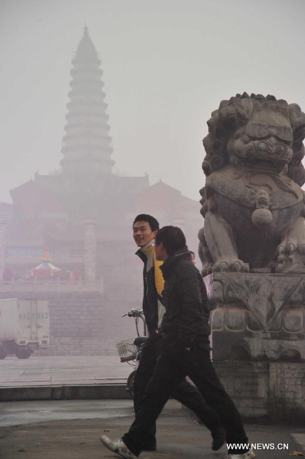 Citizens walk past the fog-shrouded pagoda of the Longxing Temple in Xinjiang County of Yuncheng City, north China's Shanxi Province, Dec. 16, 2012. A heavy fog hit Shanxi on Sunday. (Xinhua/Gao Xinsheng)