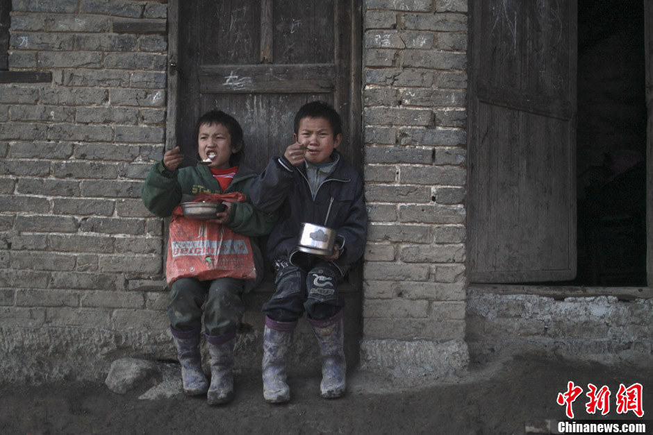 Children queue to get lunch in front of the kitchen of their teacher Tao Jinjun at every noon. Their garnishes are just a small amount of potato and a sauerkraut soup. (Chinanews/Feng Zhonghao)