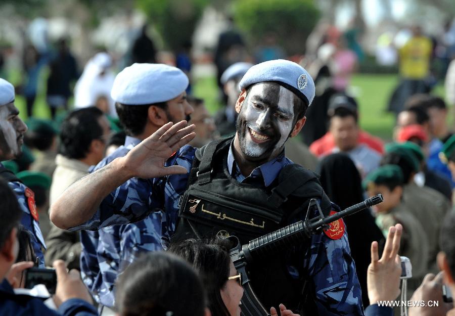 A soldier waves hands to people after a military parade during Qatar's National Day in Doha, Qatar, on Dec. 18, 2012. (Xinhua/Chen Shaojin)