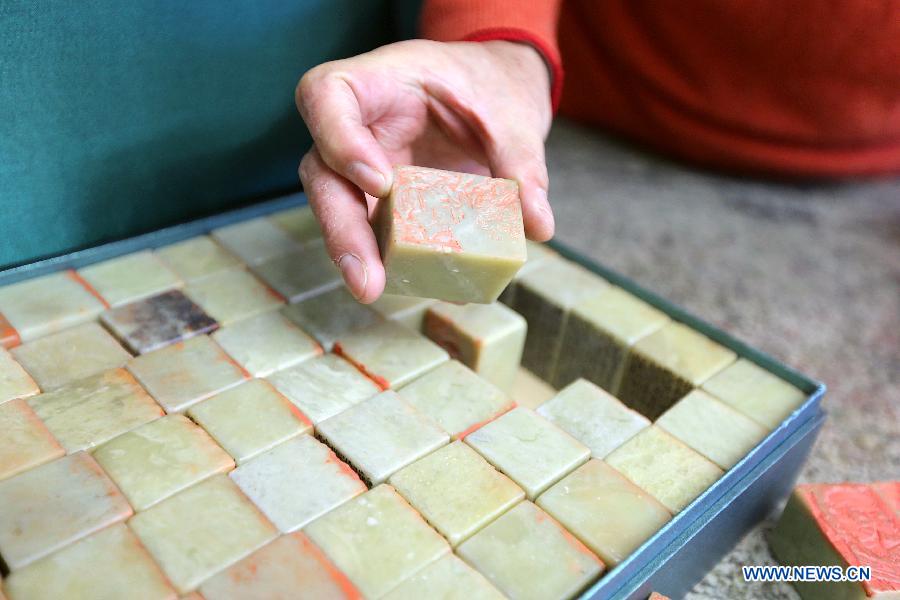 Zhang Gengyuan, a portrait seal cutting master, displays his portrait seals in his studio in Hangzhou, capital of east China's Zhejiang Province, Dec. 4, 2012. (Xinhua/Zhang Chuanqi)